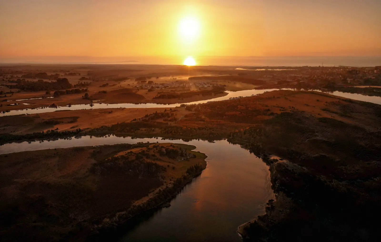 Vista aérea do Rio Mampituba ao pôr do sol, em Torres, com os meandros do rio e a área do condomínio